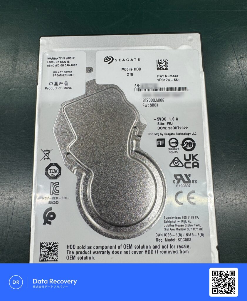 データ復旧のため入庫した外付けHDDの内蔵ドライブ、Seagate Mobile HDD ST2000LM007（2TB・2.5インチSATA HDD）の裏面ラベル。「通電するが認識しない」症状で受領